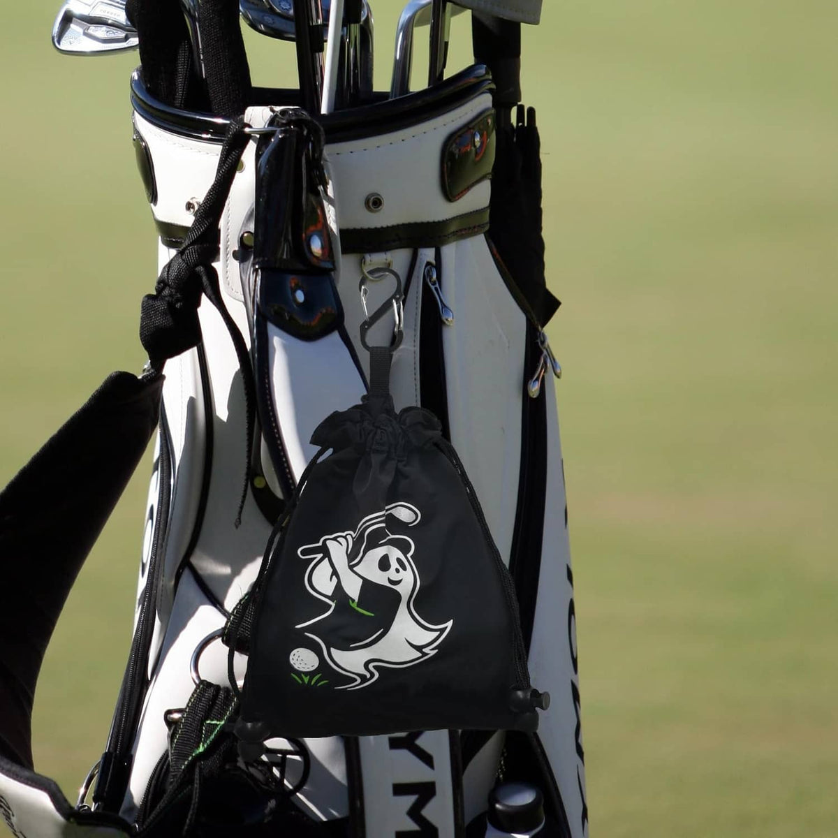 Black drawstring pouch with white golfer graphic clipped to a golf bag frame.