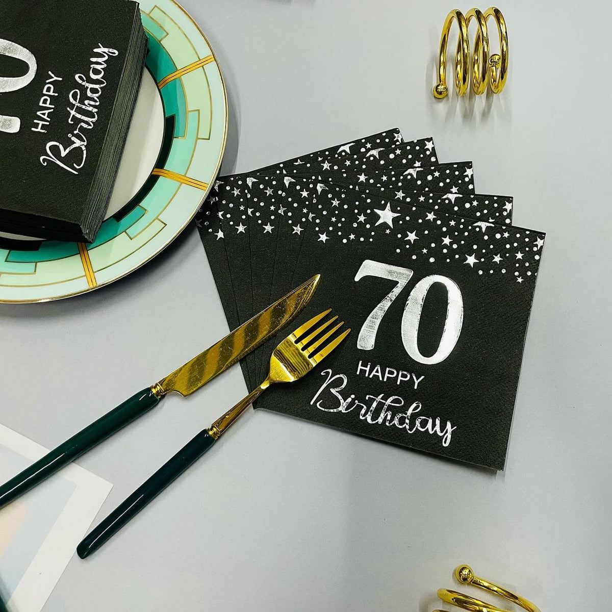 Black star 70th birthday napkins with silver “70 Happy Birthday” at place setting