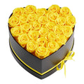Yellow preserved roses in a heart-shaped black gift box with yellow ribbon