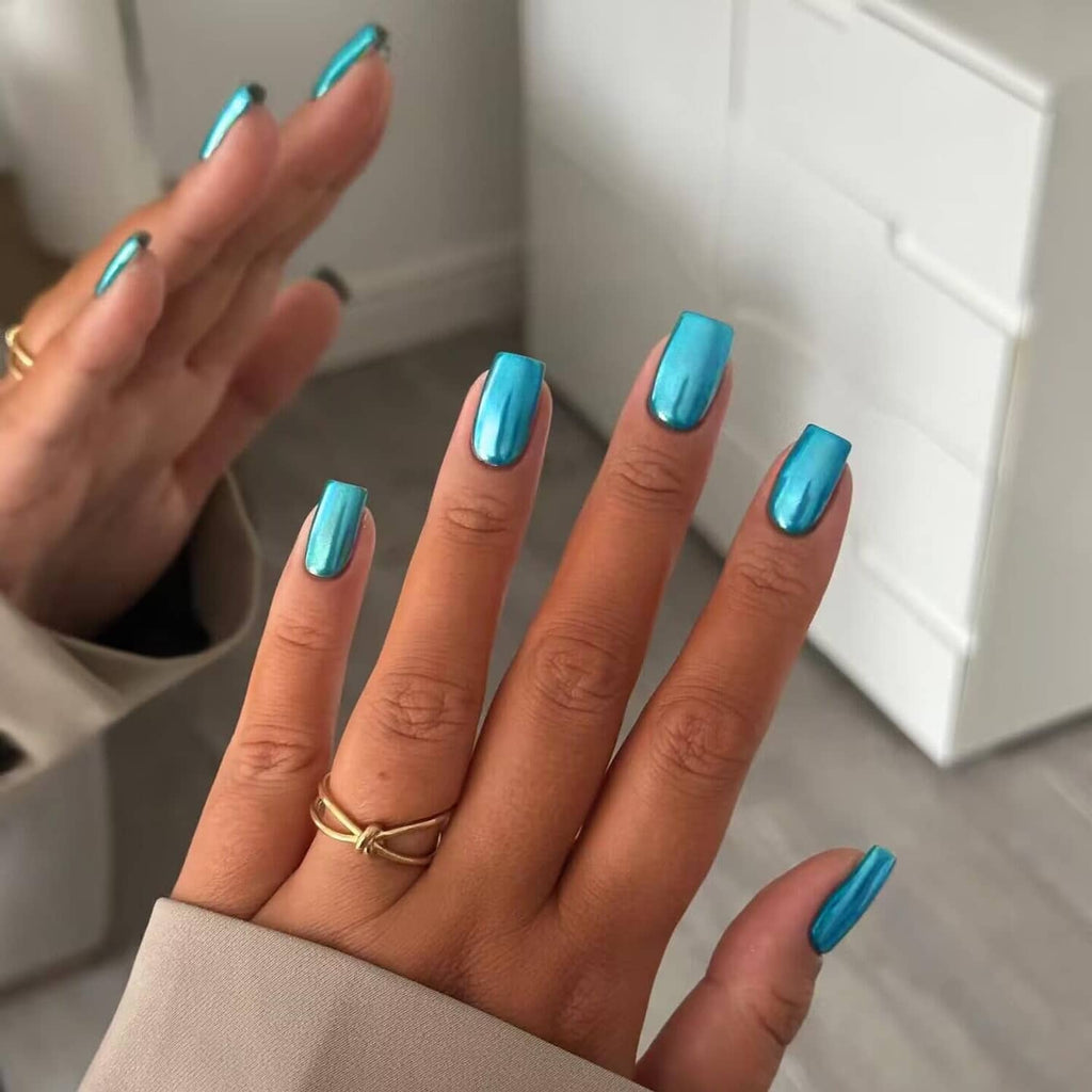 Teal blue chrome square press-on nails displayed on hand with ring on finger.