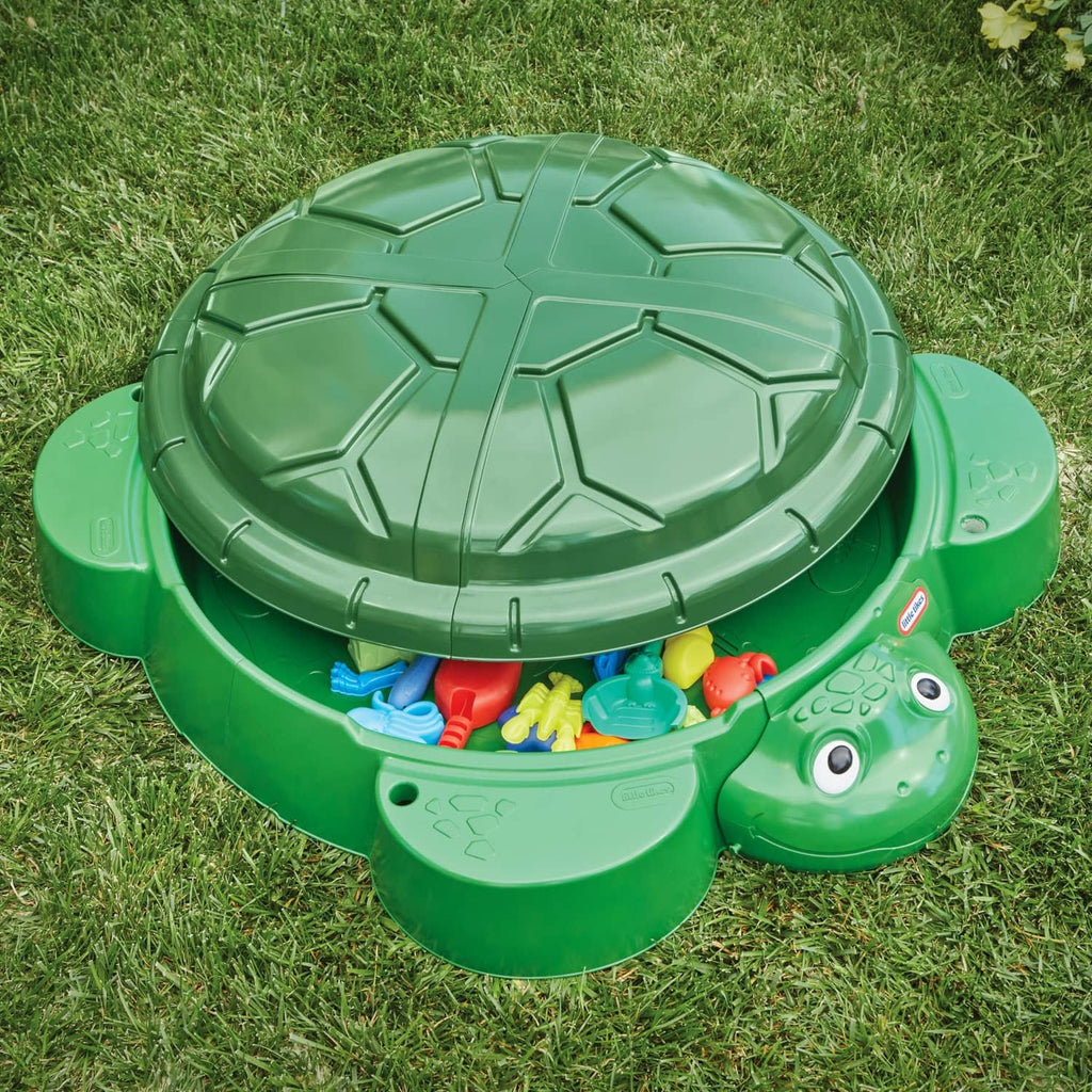 Open green turtle sandbox with lid up and colorful plastic accessories inside