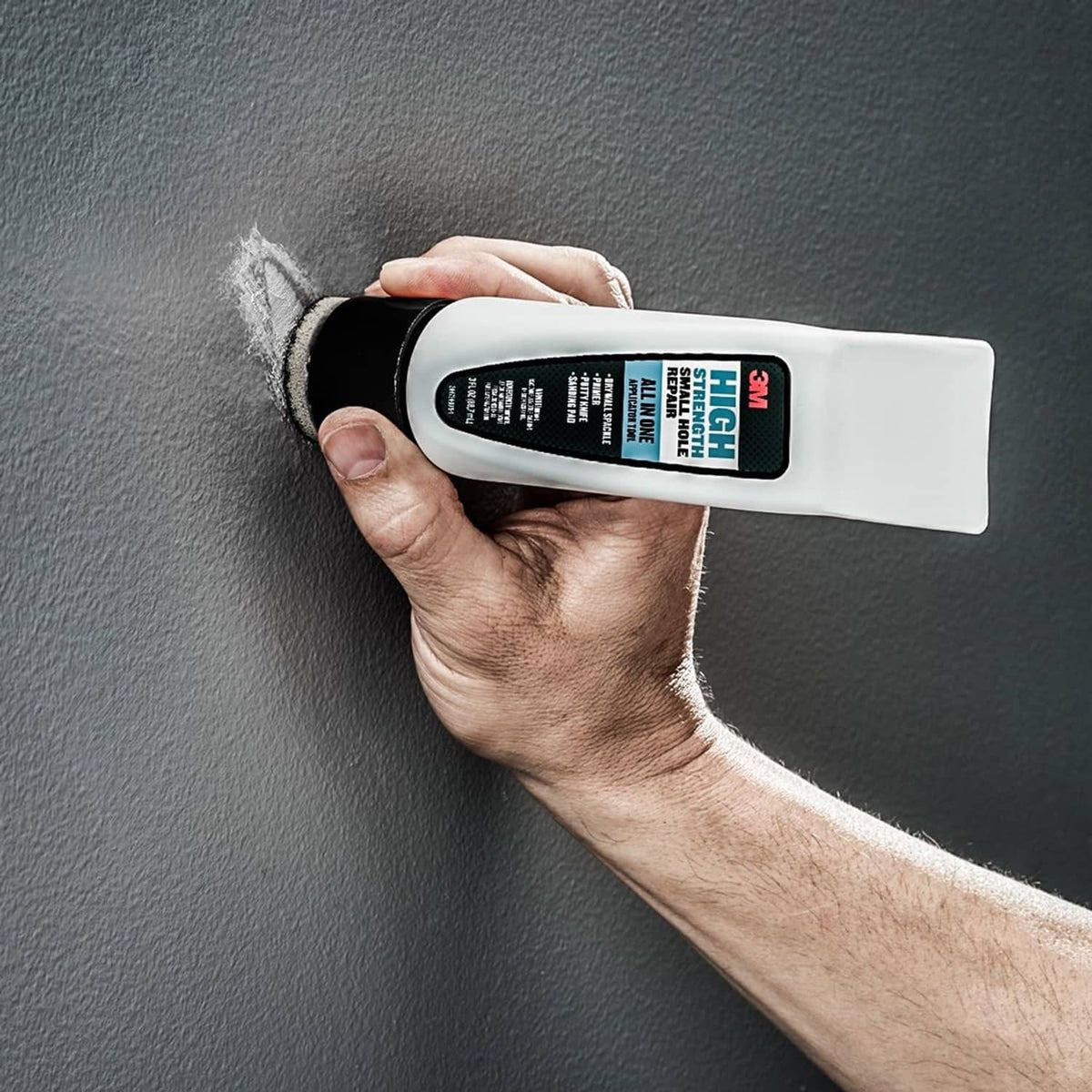 White repair applicator tool sanding over a repaired small hole on textured wall