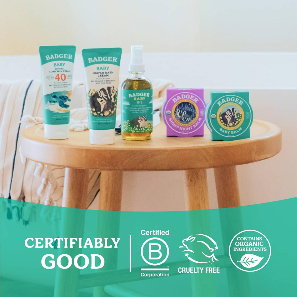 Set of BADGER Baby products on a round wooden table, including diaper rash cream tube