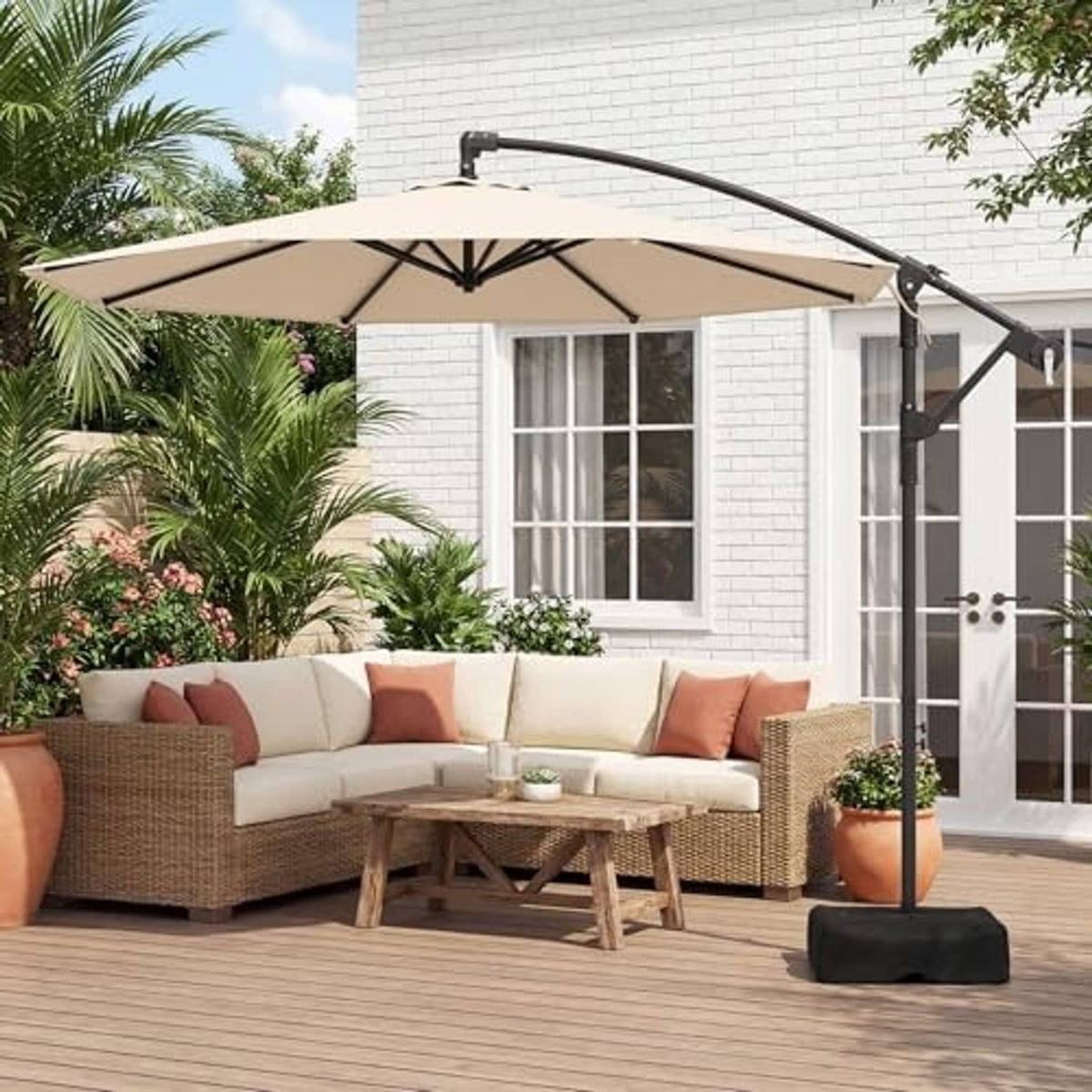 Offset cantilever patio umbrella with beige canopy on black stand and base in outdoor patio