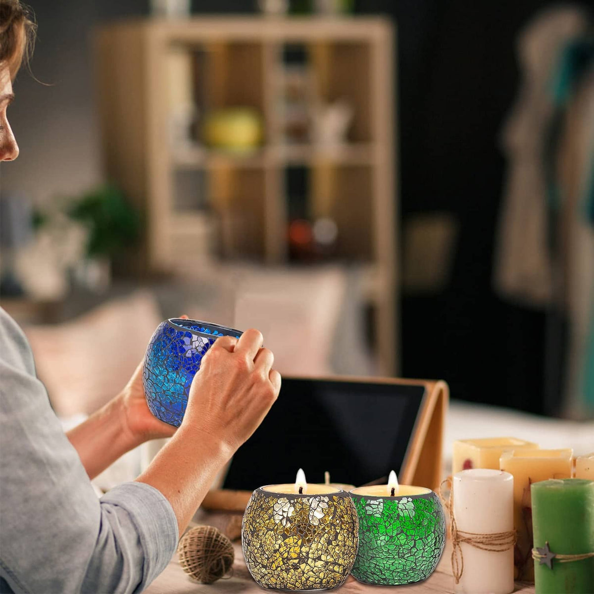 Blue mosaic glass votive candle holder held in a hand, round tea-light cup.