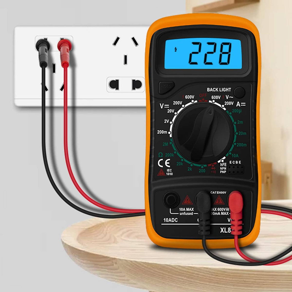Digital multimeter with orange casing and red/black test leads