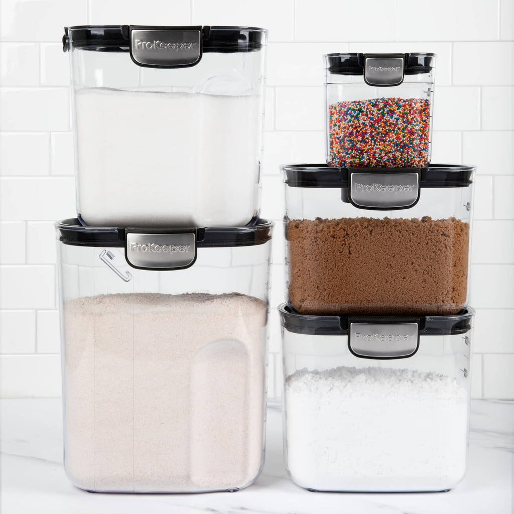 Clear plastic airtight containers with black lids, filled with flour, sugar, and sprinkles