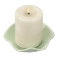 Light green lit candle in leaf-shaped holder