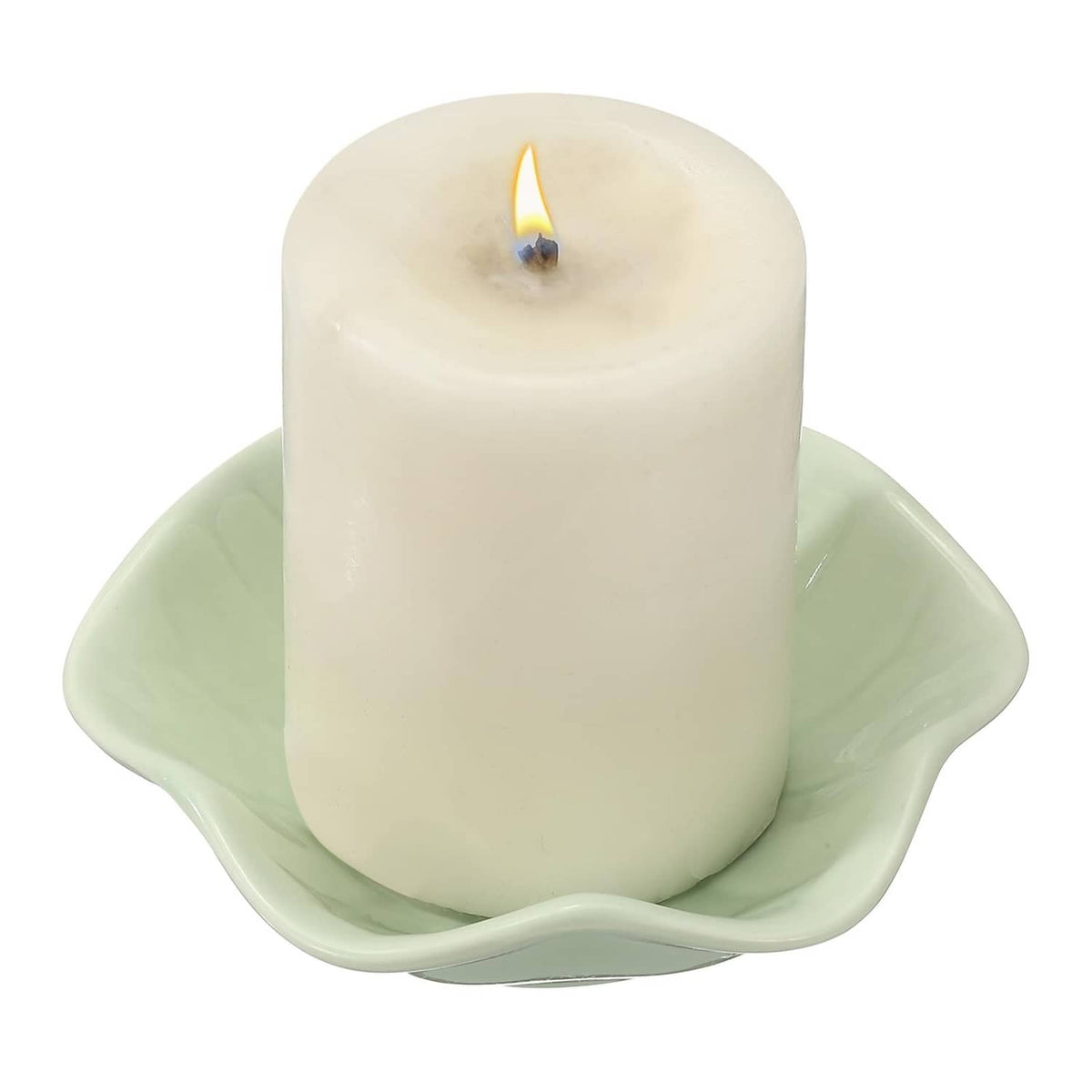 Light green lit candle in leaf-shaped holder