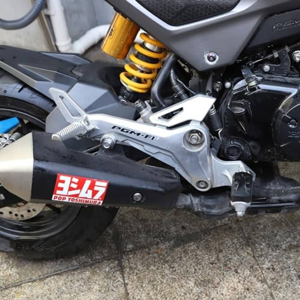 Silver right-side footrest with black rubber pad on motorcycle near engine