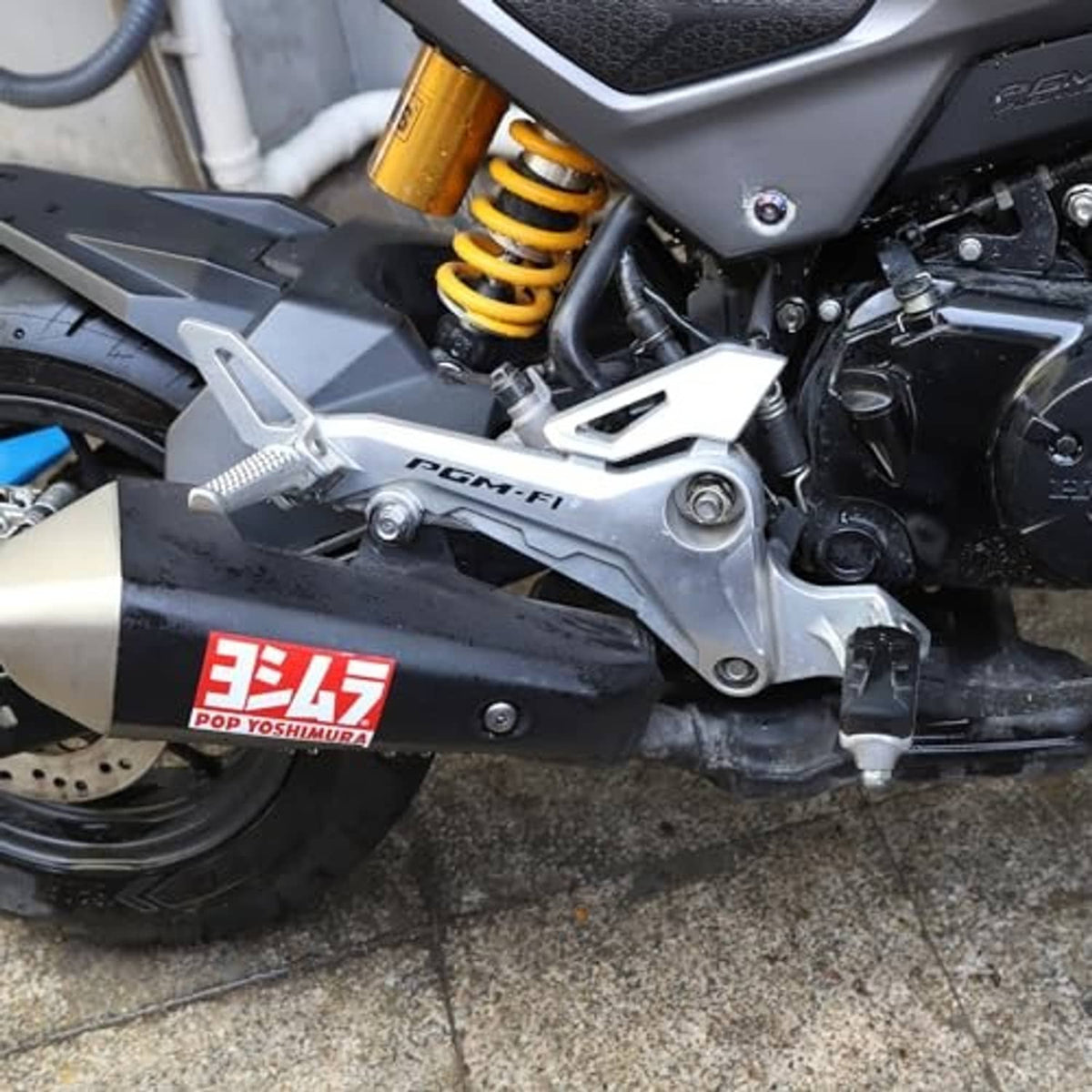 Silver right-side footrest with black rubber pad on motorcycle near engine