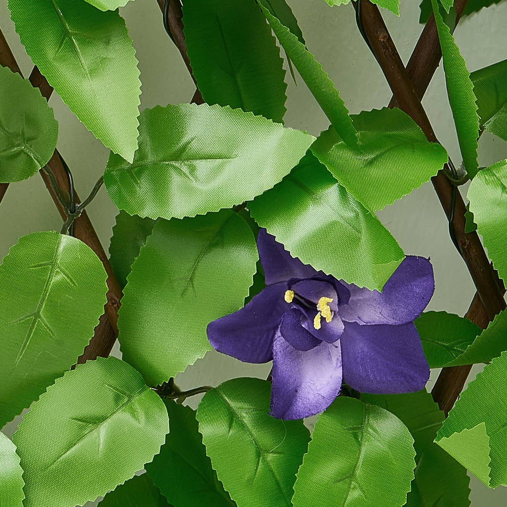 Close-up of artificial ivy leaves with purple flowers on woven screen