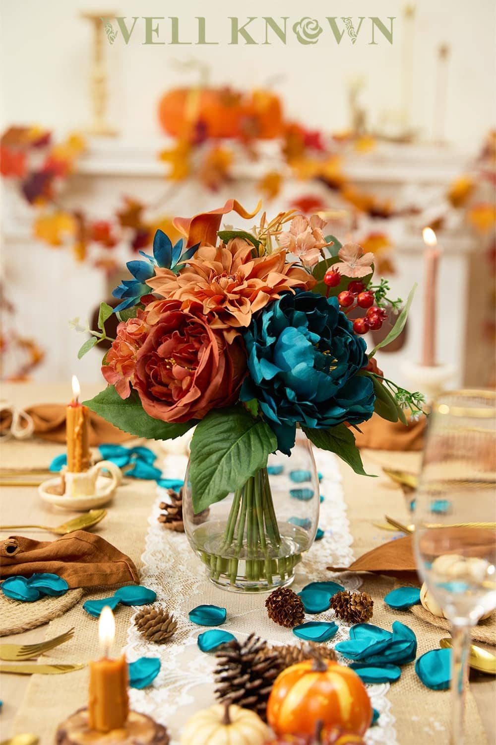 Faux flower bouquet in clear glass vase with teal and orange blooms and berries
