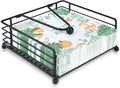 Black metal napkin holder with crisscross base, holding folded botanical-pattern napkins