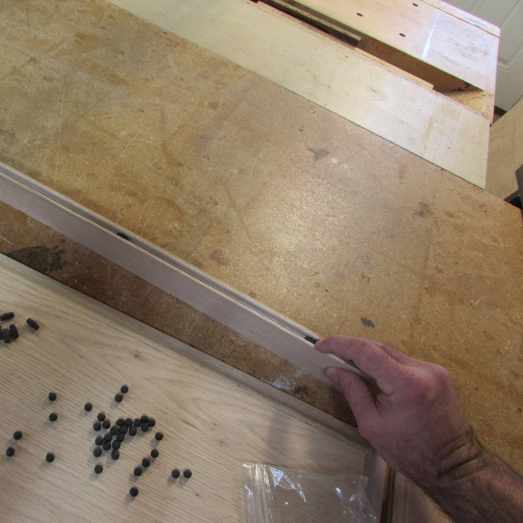 Hand placing black rubber ball door spacers in wood track