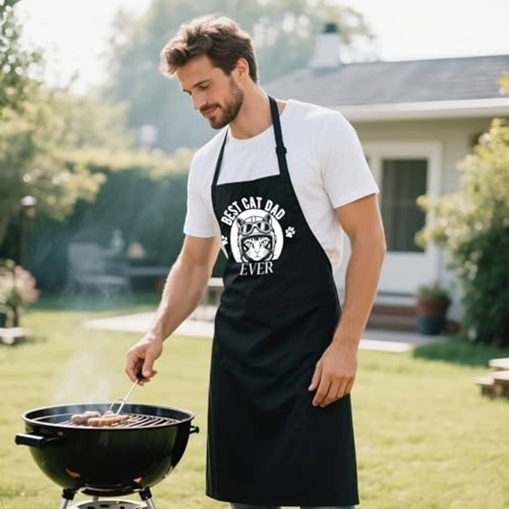 Black BBQ apron with 'Best Cat Dad Ever' cat print and adjustable neck strap.
