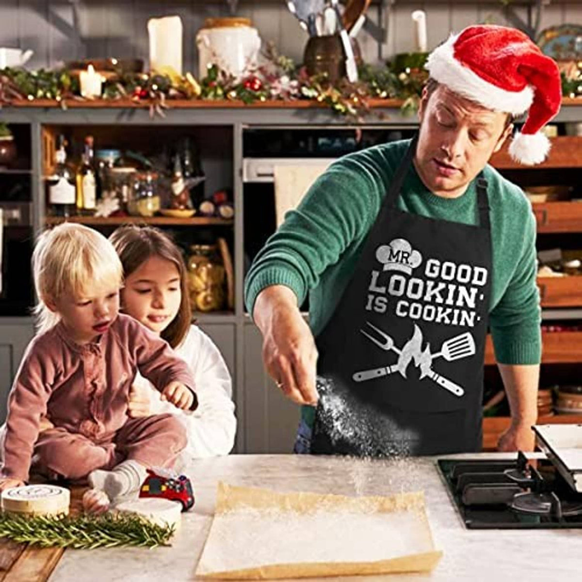 Black cotton cooking apron worn with 'MR. GOOD LOOKIN' IS COOKIN' graphic