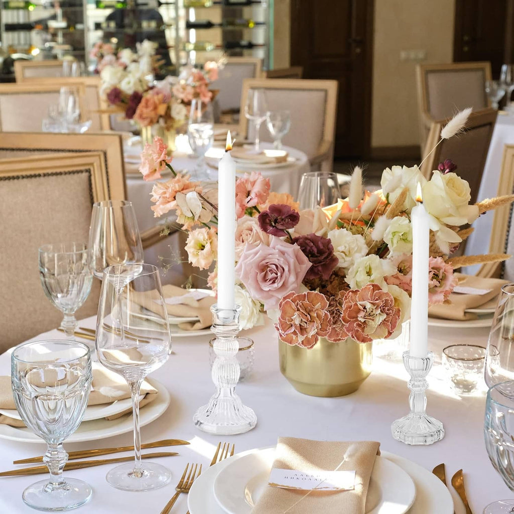 Clear glass taper candle holders among a floral table centerpiece with taper candles
