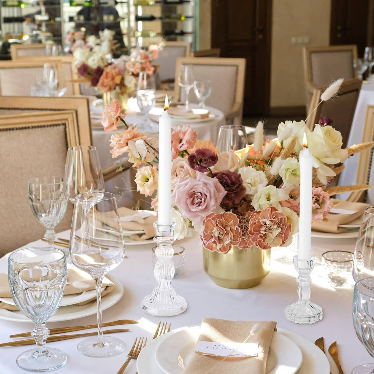 Clear glass taper candle holders among a floral table centerpiece with taper candles