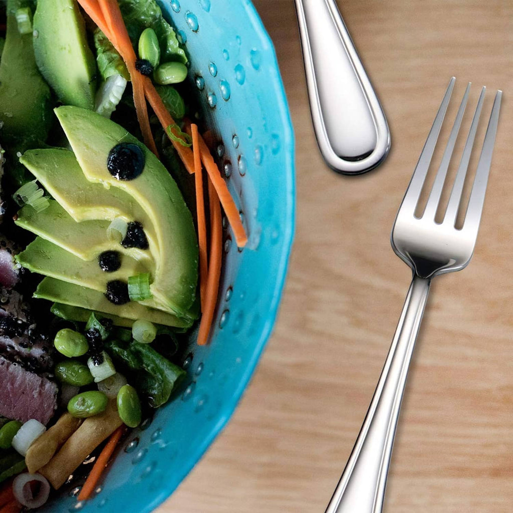 Stainless 7-inch salad fork with 3 tines near a tray of mixed vegetables