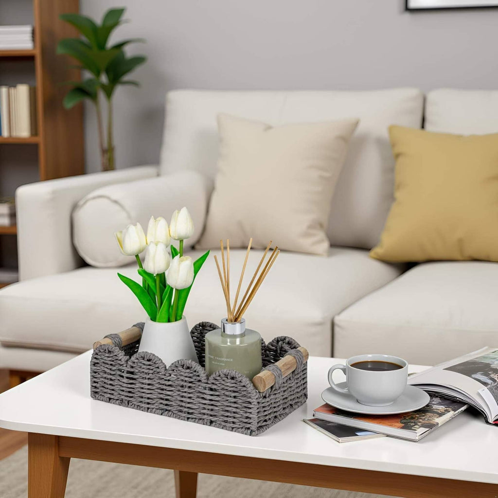 Grey scalloped storage basket with woven texture and wood handles, holding bathroom items and rolls.
