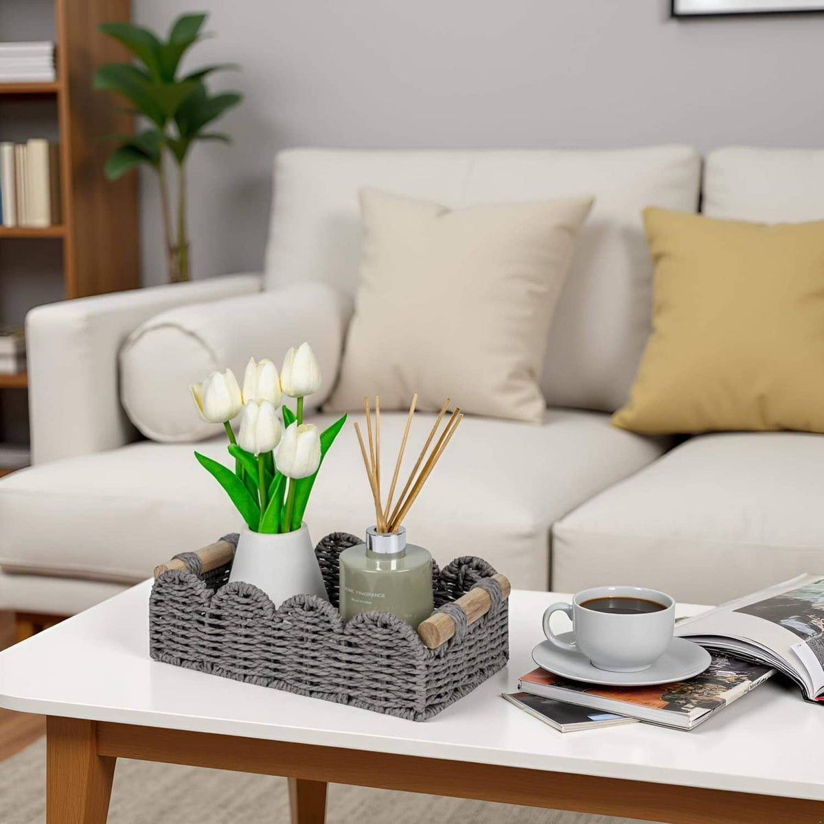 Grey scalloped storage basket with woven texture and wood handles, holding bathroom items and rolls.