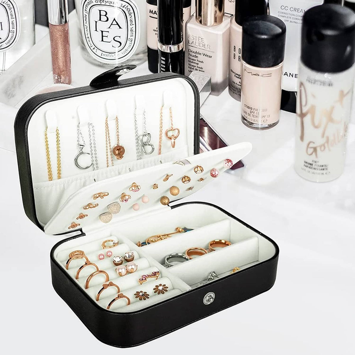 Black travel jewelry box open with white earring row and ring compartments inside