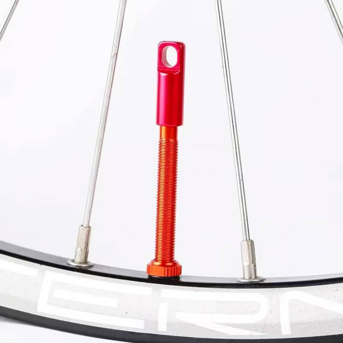 Red Presta valve stem cap with threaded core on bike wheel rim