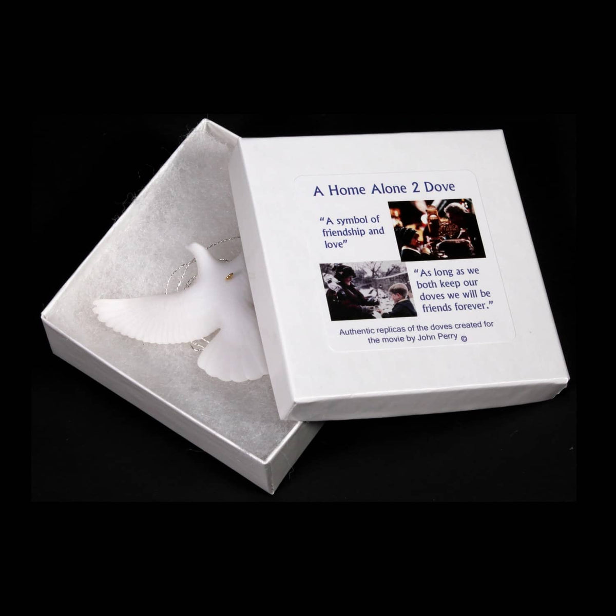 White turtle dove ornaments displayed in an open box with info card on top