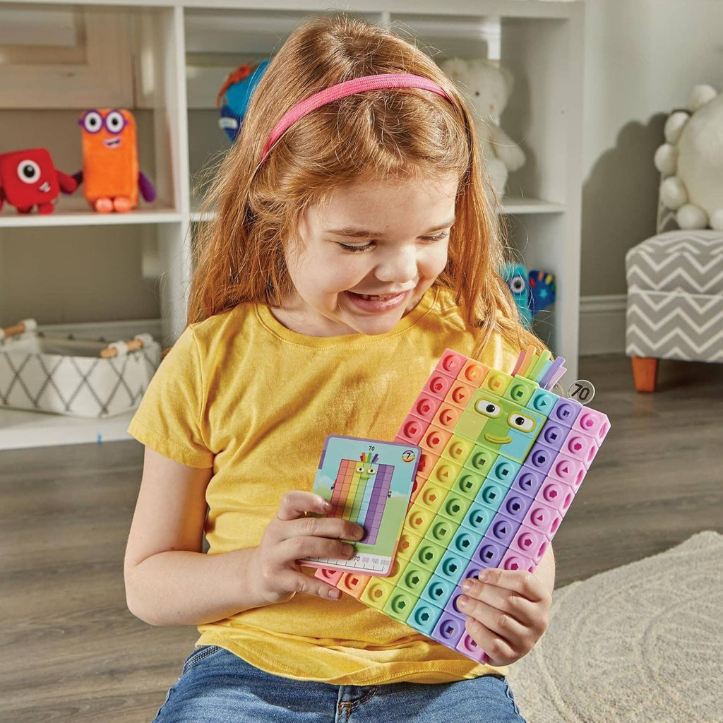 Child holding a multicolor Numberblocks cube grid board with face character