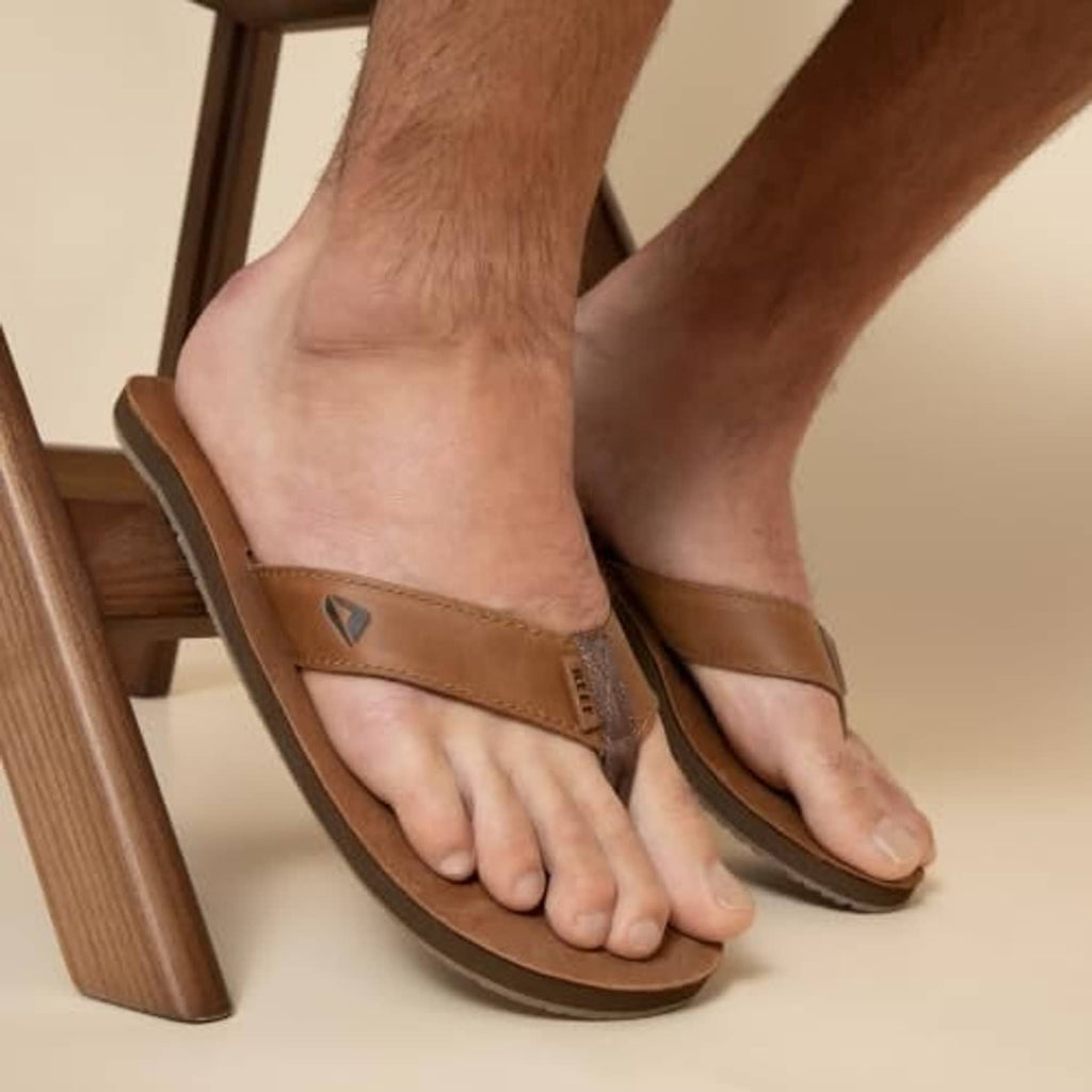 Brown leather flip-flop sandals on feet, open-toe thong style with padded strap