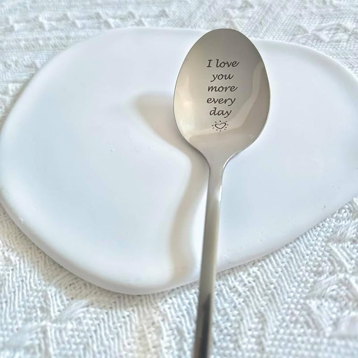 Engraved love message spoon with oval beige bowl and silver handle, 'I love you more every day'