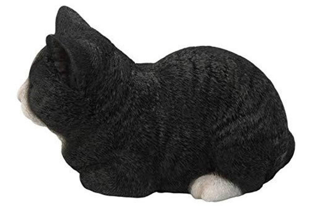 Sleeping cat statue, black with white paw, side-lying pose with tail visible