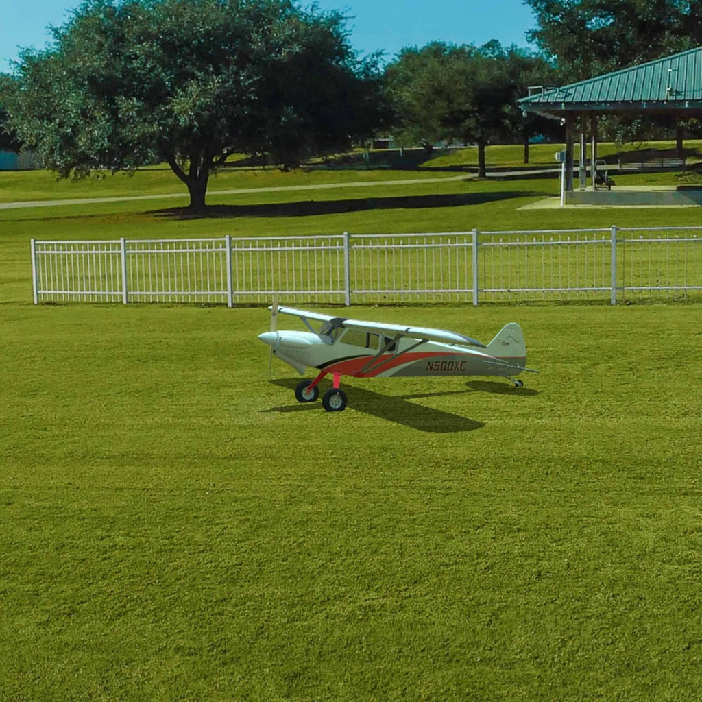 White and red RC airplane resting on grass