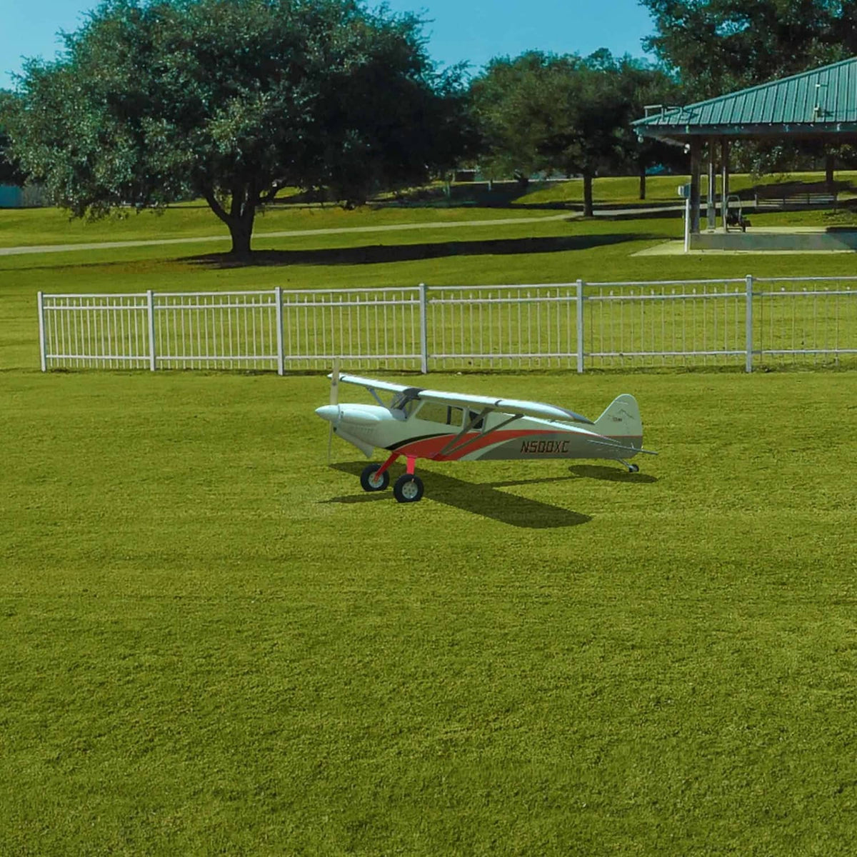 White and red RC airplane resting on grass