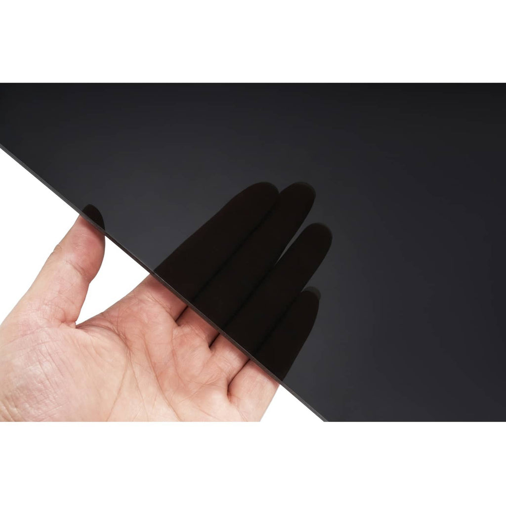 Dark tinted windshield panel held by hand, smooth surface with dark gray finish