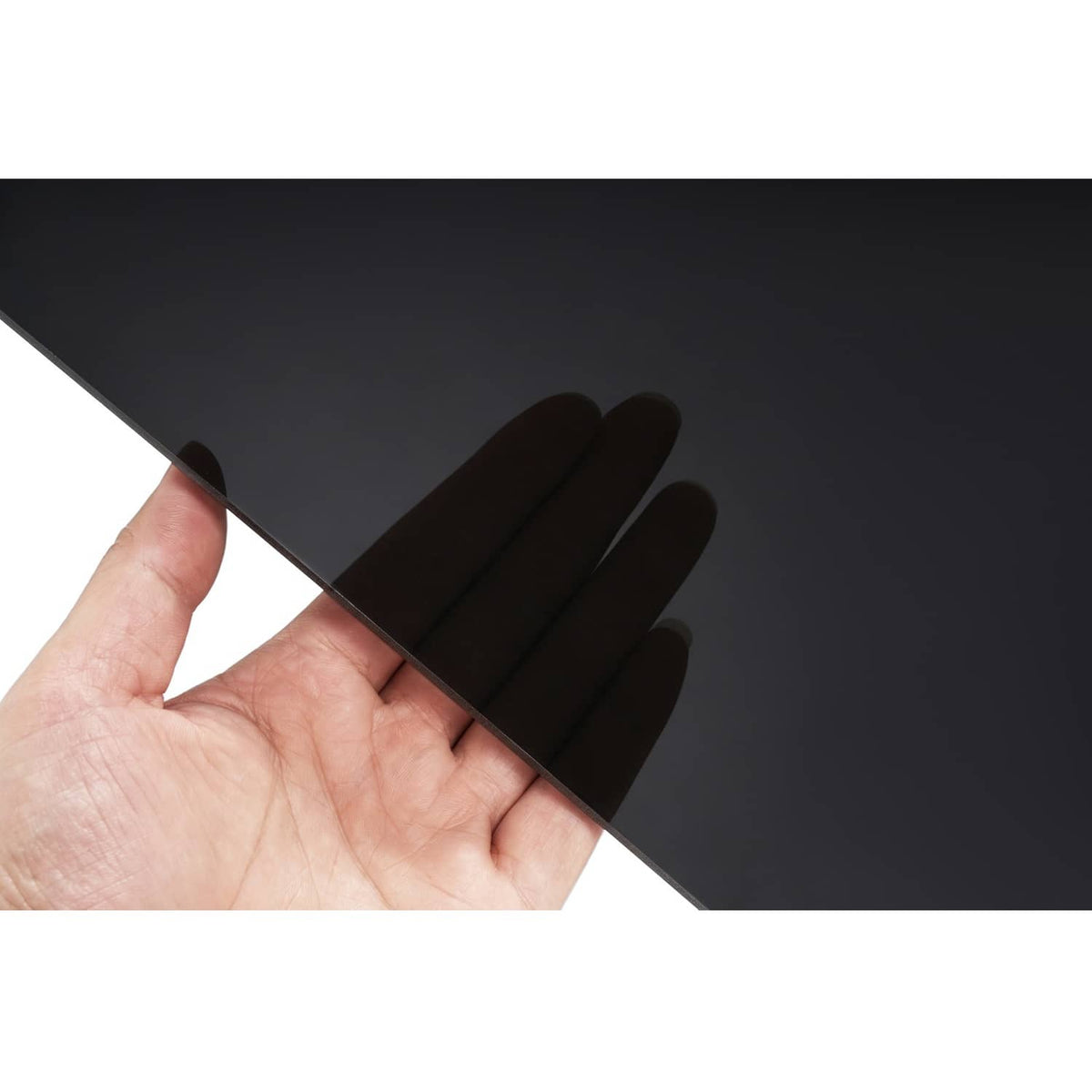 Dark tinted windshield panel held by hand, smooth surface with dark gray finish