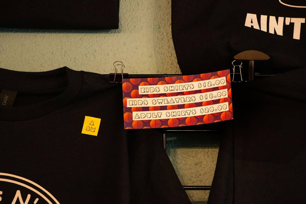 Black T-shirt on display with colorful price tags clipped across the fabric
