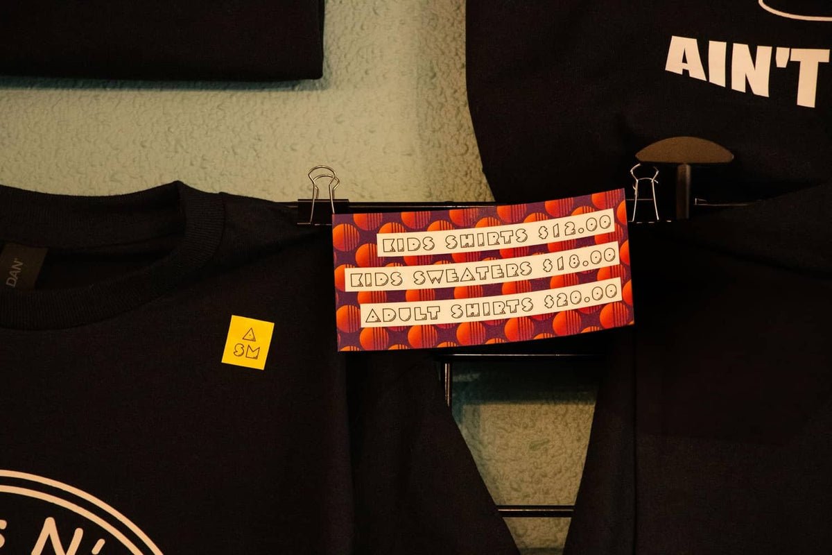 Black T-shirt on display with colorful price tags clipped across the fabric