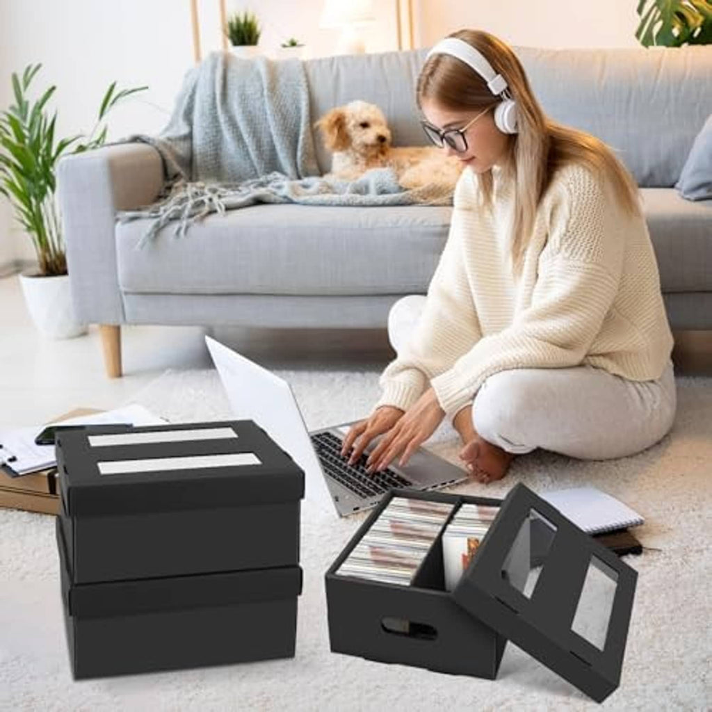 Two-compartment black CD storage box with lid open while loading discs.