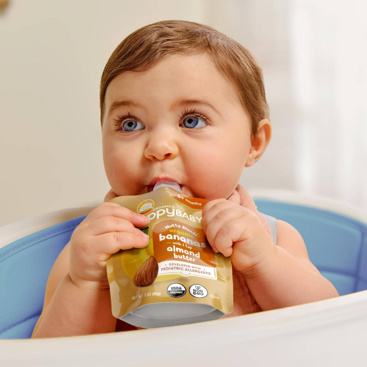 Baby holding a HappyBABY Stage 2 nutty blends pouch, bananas with almond butter