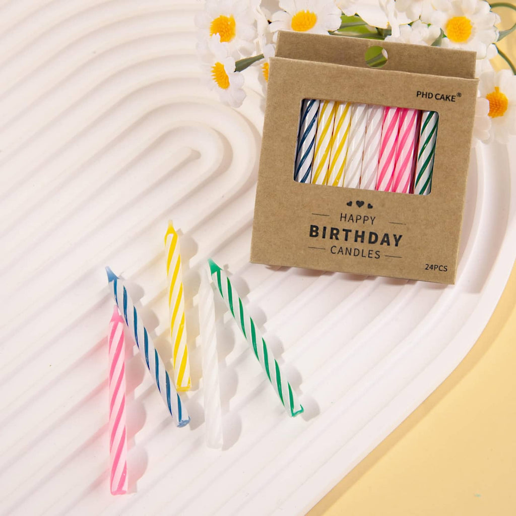 Happy Birthday candle box with multicolored striped candles and a few loose candles