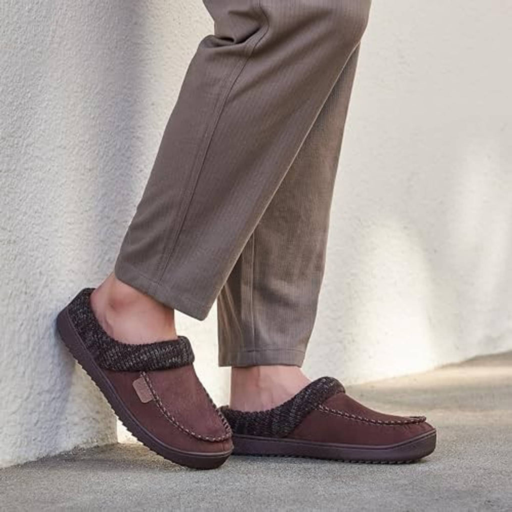 Brown moccasin clog slippers with dark knit cuffs worn with gray pants
