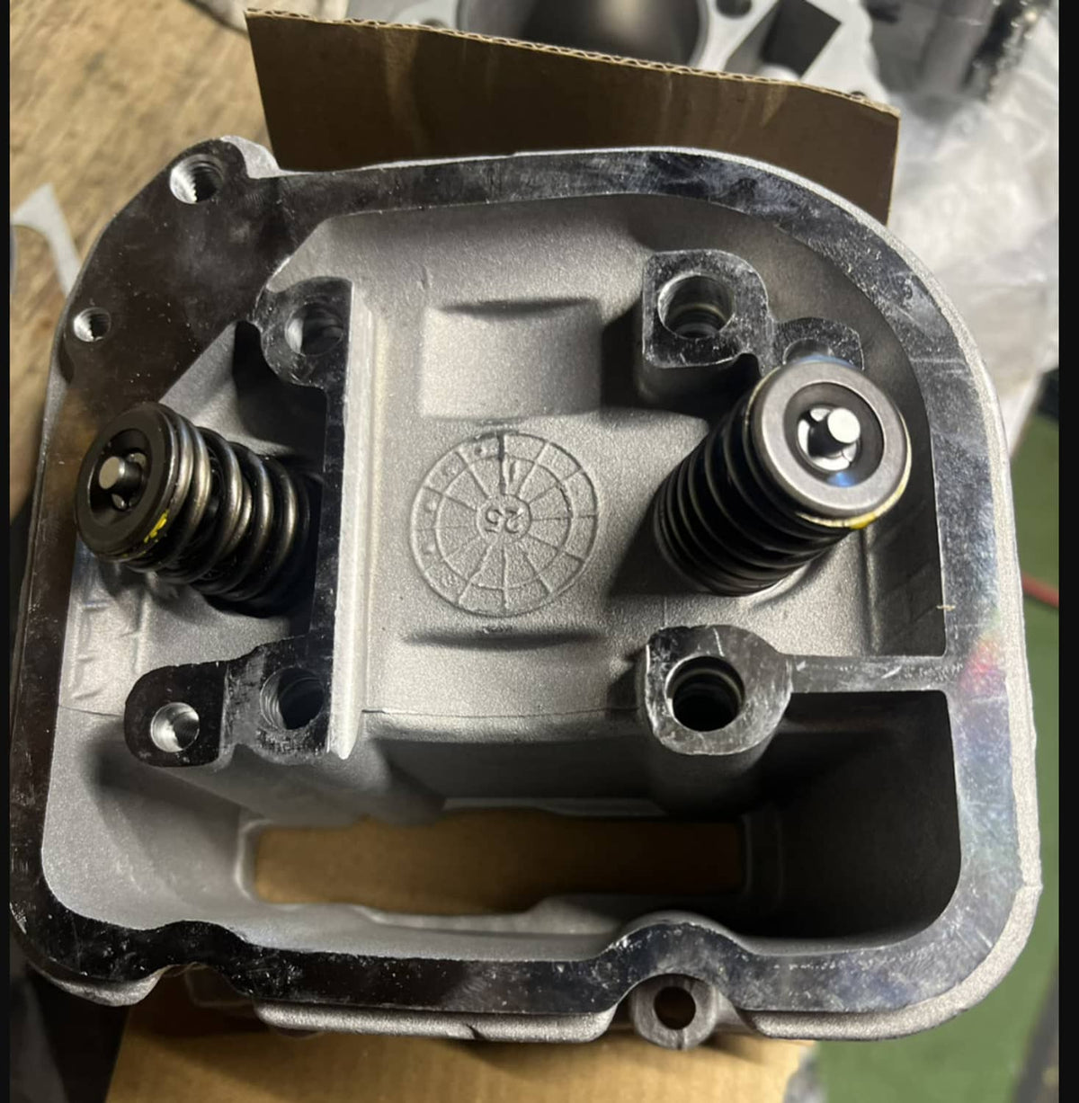Cylinder head assembly with two valve springs and fasteners on a silver metal base