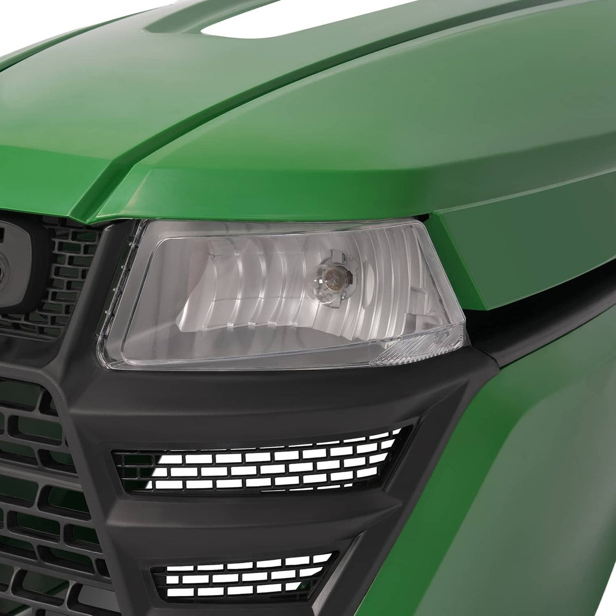 Front headlight assembly on green lawn tractor: clear lens and black grille