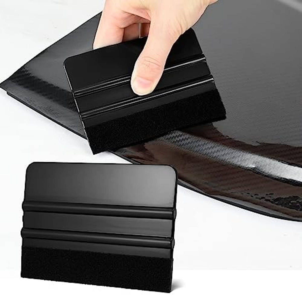 Black felt squeegee smoothing vinyl wrap, pressed under a hand.