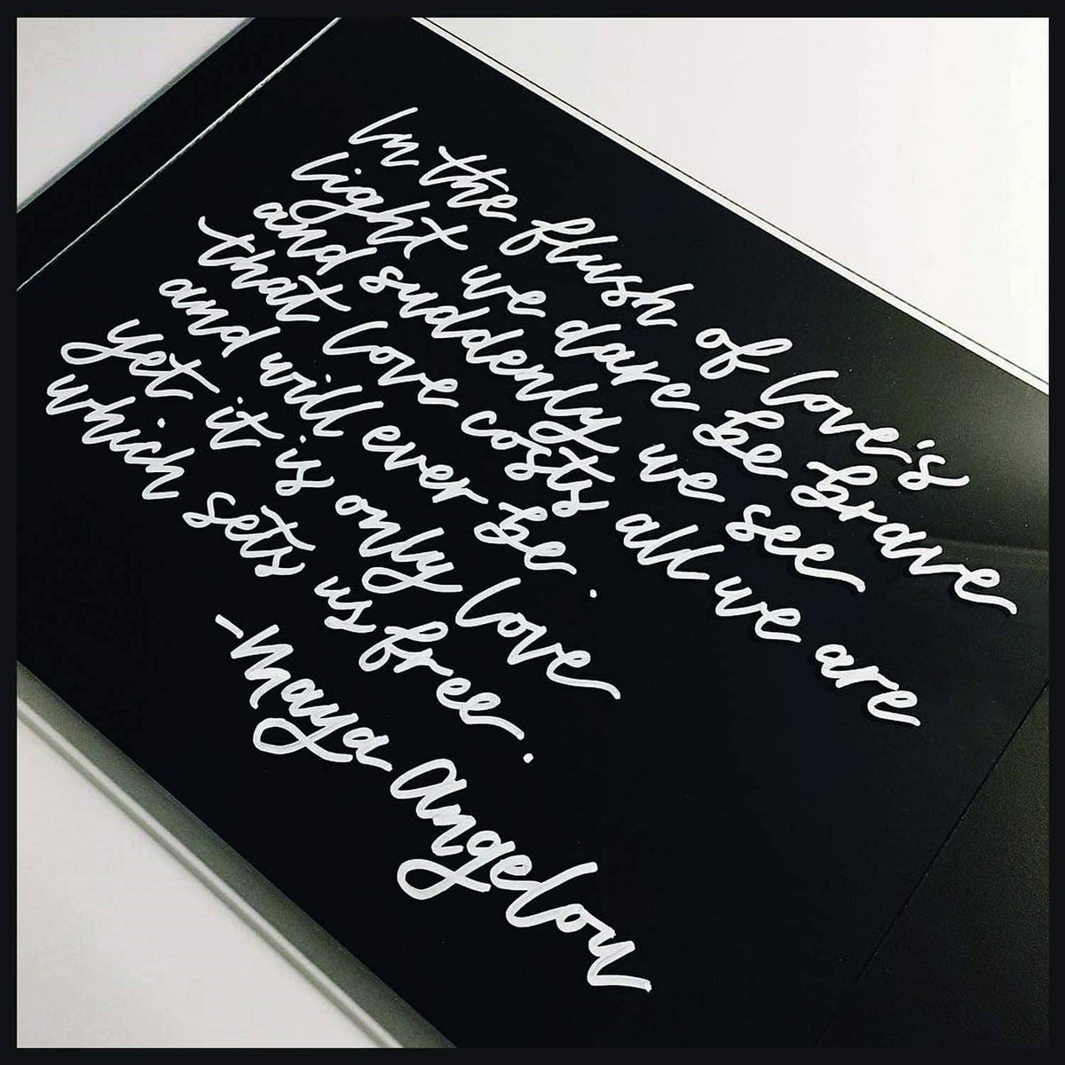 Paint pen lettering on dark paper with white cursive script and small accents