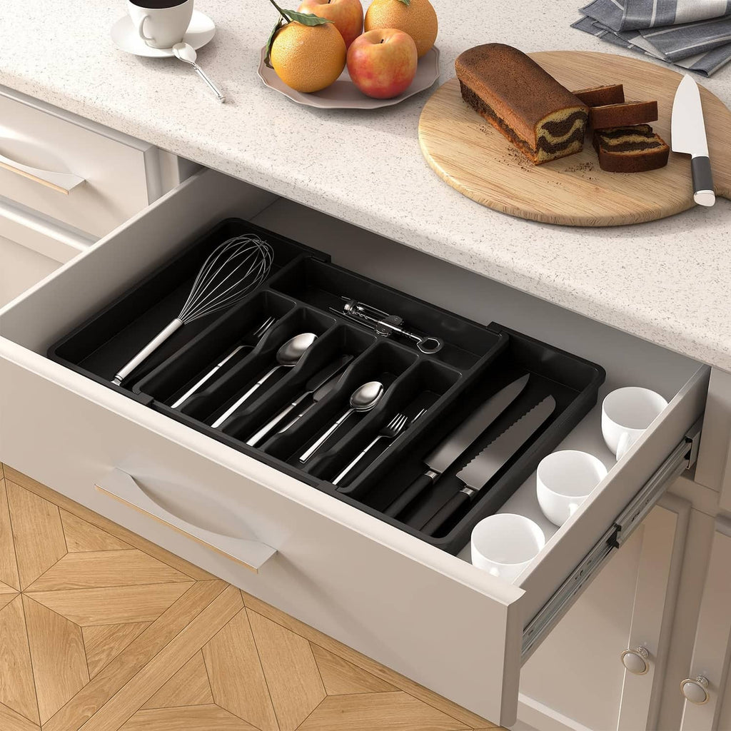 Dark utensil organizer tray with spoons, forks, and cups inside a kitchen drawer