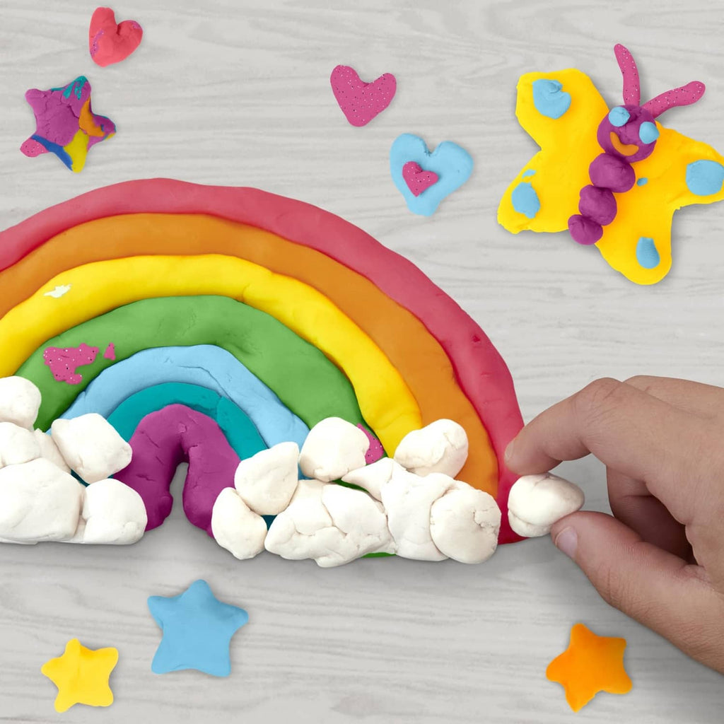 Play-Doh rainbow arc with white rocks and star and heart shapes, on board