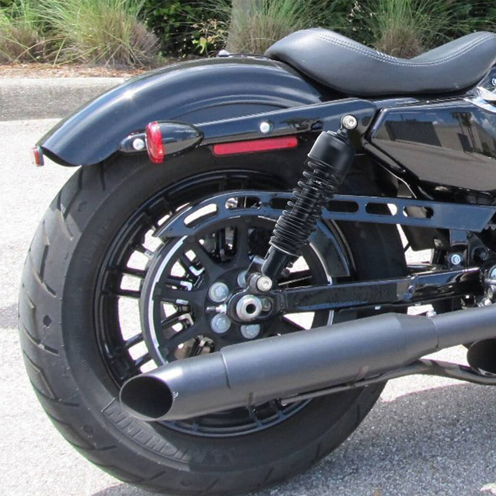 Rear suspension shock mounted on a motorcycle, with black coil spring and chrome exhaust